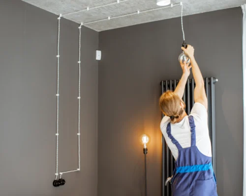 worker installing some lights on a house with grey walls